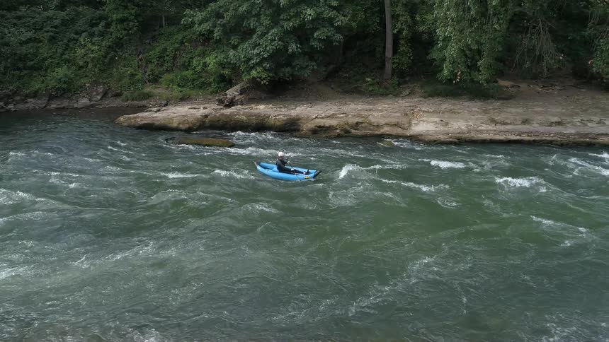 Aerial of a person on a kayak paddling in strong current on a river