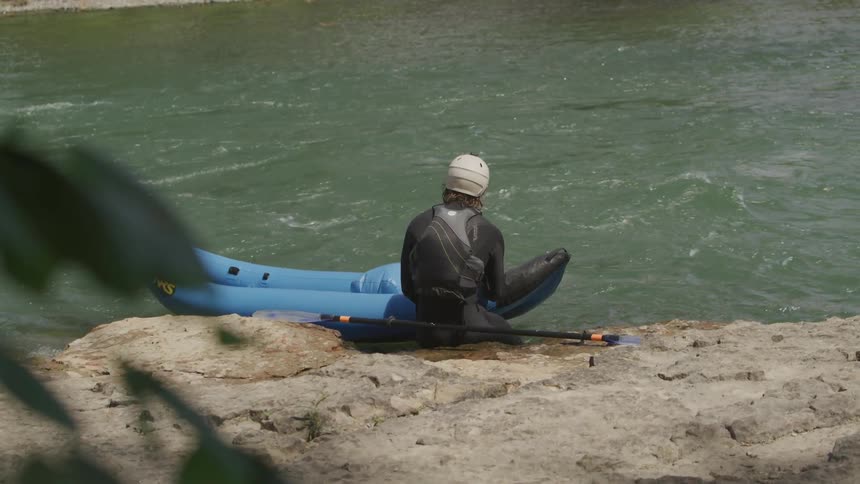 A man waiting on the river bank with his canoe