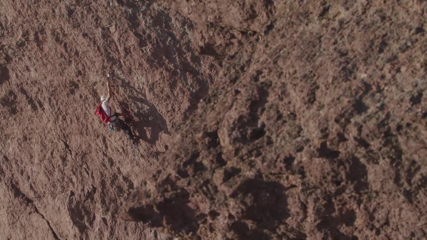 A man climbing a large rock overhang