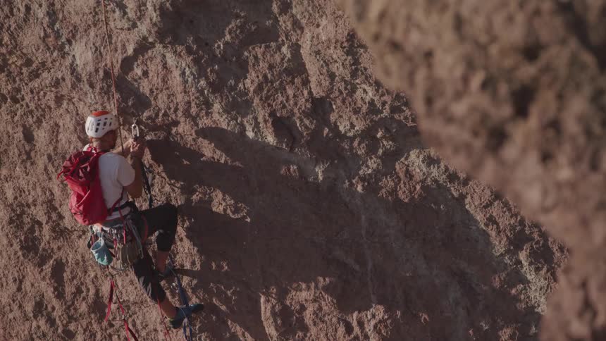 A rock climber makes his way up the side of a cliff