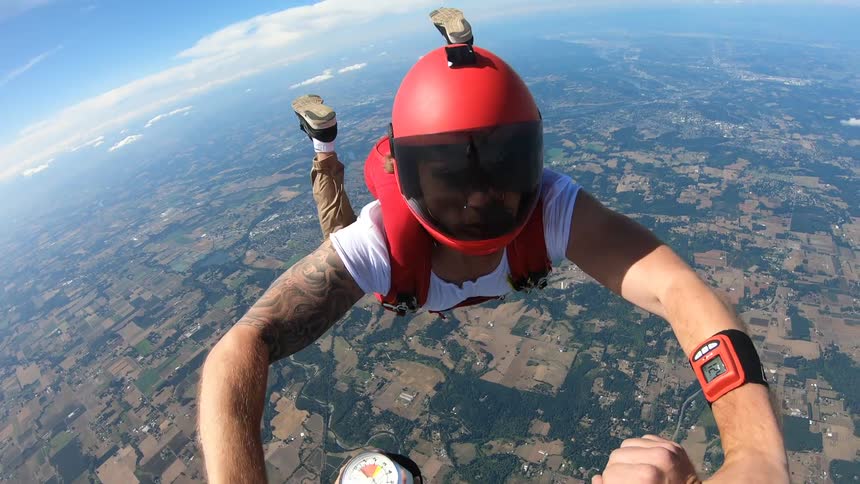 A skydiver flies over and grabs hands with another before letting go and flying away