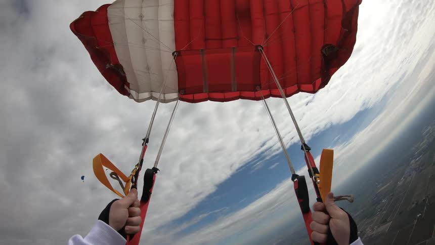 Person parasails over city under cloudy sky