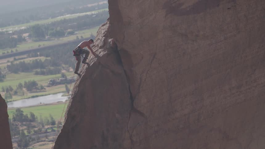 Man free climbs sloping rock face