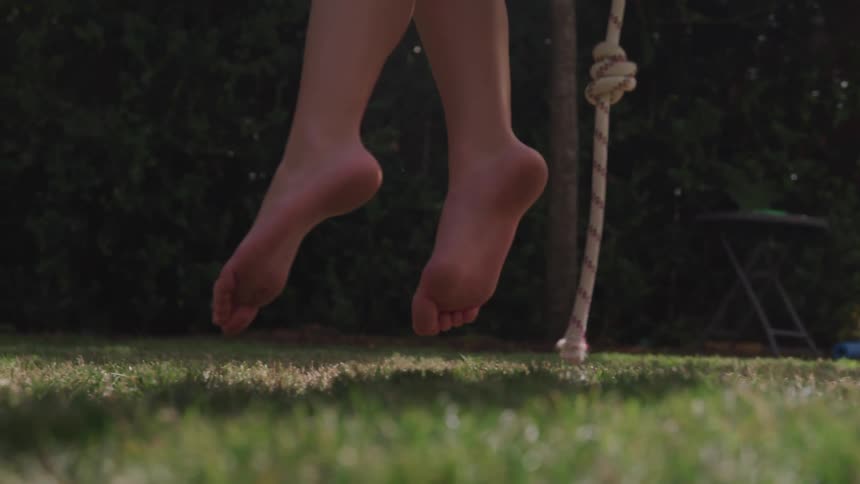 A close up view of child feet playing swing at the playground
