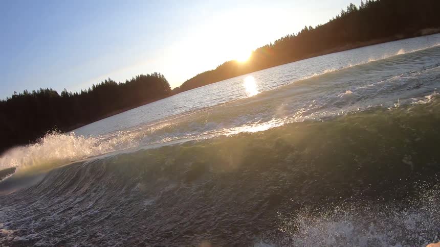 A water skier holds onto the rope as he gets pulled through the boat wake