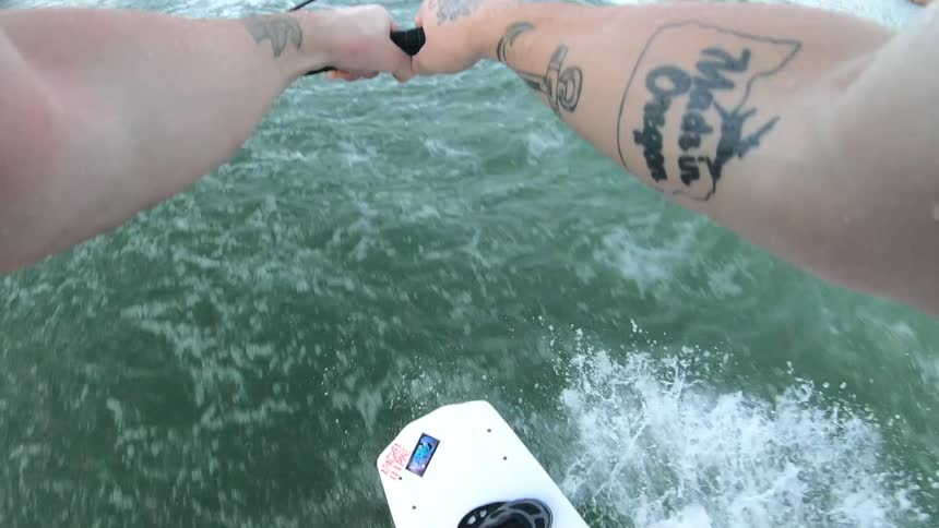 Point of view shot of a wake boarder being towed by a boat on a lake