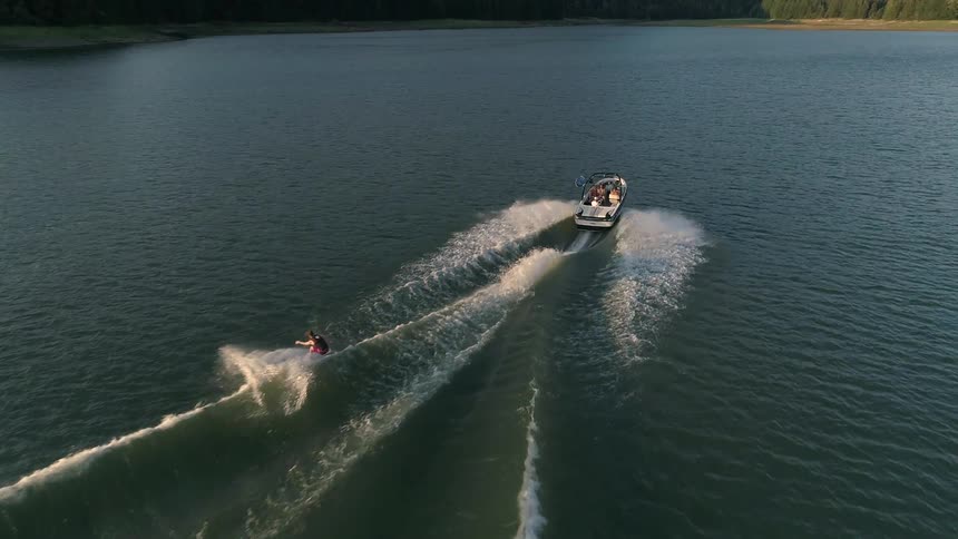 Male wake boarder being pulled by a boat on a lake