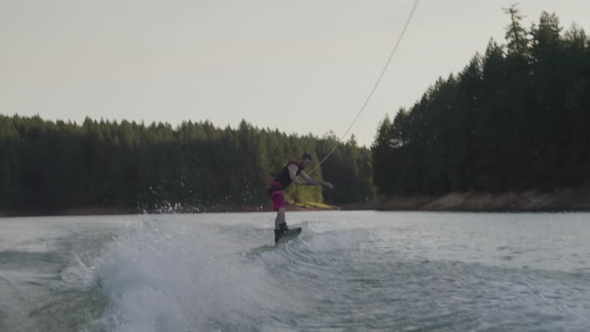 A young man does a flip and then falls while water skiing