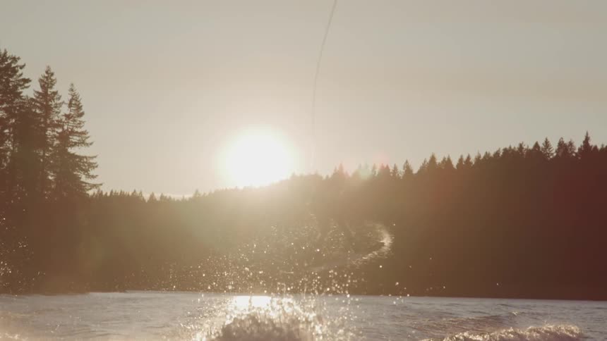 A person on a water board jumps a wave kicked up by the boat