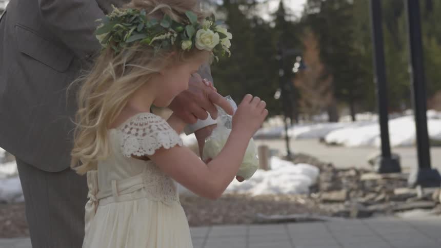 Flower girl is escorted as she spreads flower petals