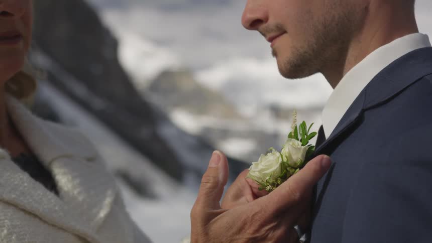 A woman pinning a flower onto a mans suit
