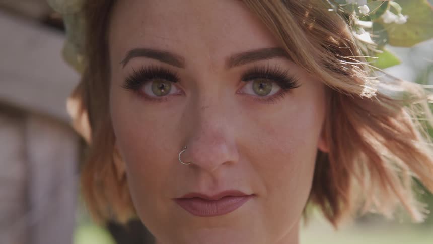 A young woman stands outside and opens her eyes wide and looks up