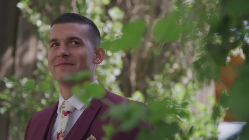 A man in a purple suit standing outside surrounded by leaves