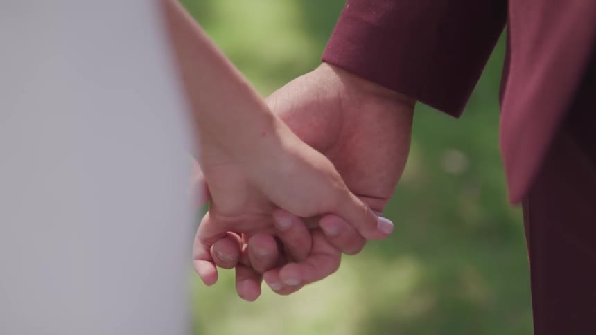 Two people hold hands standing outside
