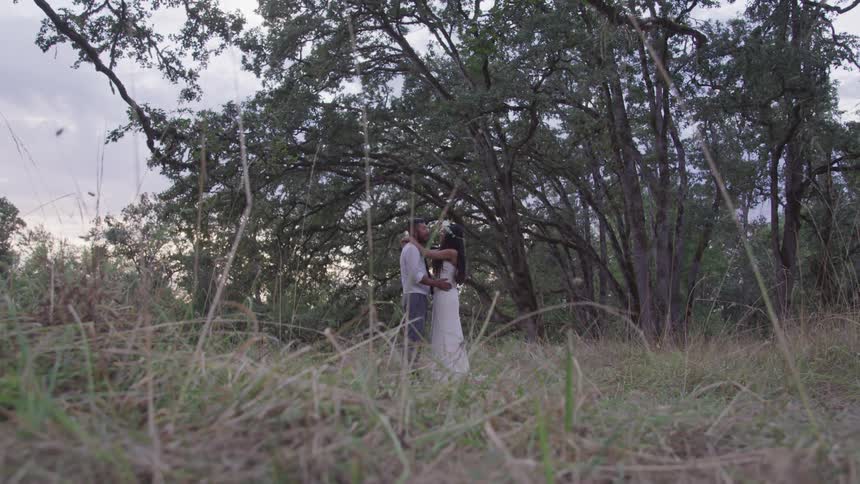 Groom and bride hold and look at each other in the forest