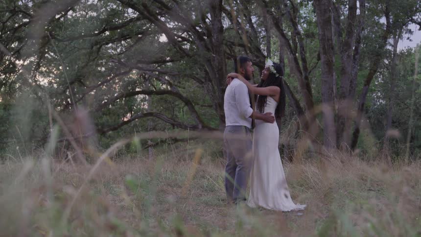 Newlyweds embracing looking at each other in field