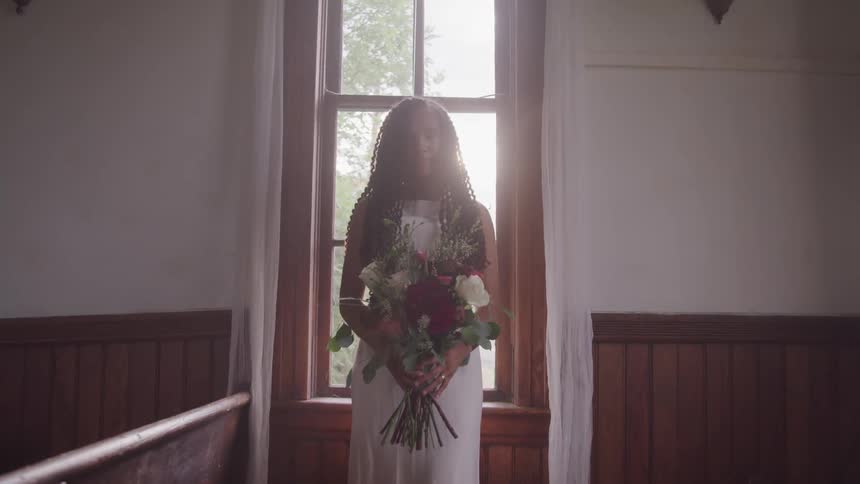 A young bride stands holding a bouquet of flowers