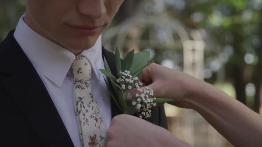 Woman placing a boutonniere on a young mans suit