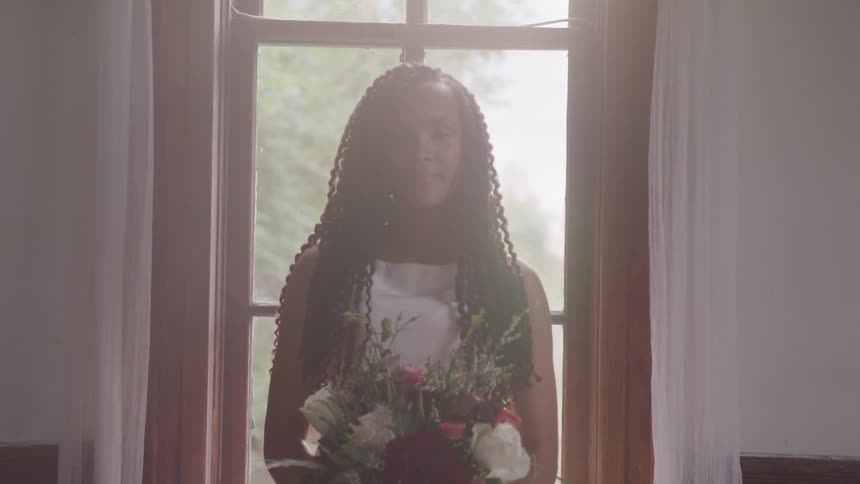 Bride holding a bunch of flowers stands in front of the window in the church