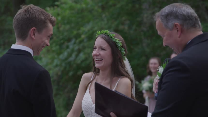 A bride and groom laugh at the minister during the ceremony