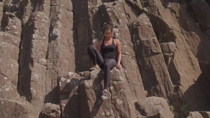 A black woman sitting on top of a rock