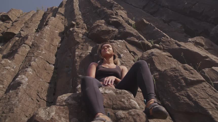 A young woman sits on a ledge on a canyon