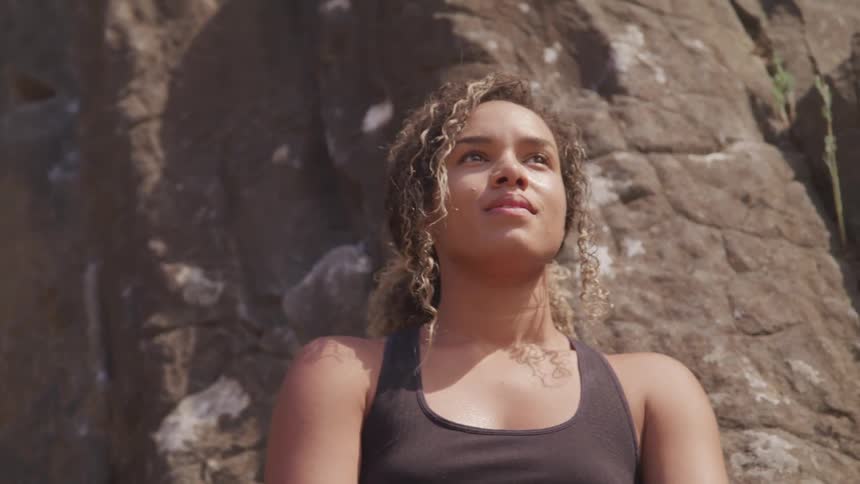 A portrait of a curly woman at the bottom of cliff