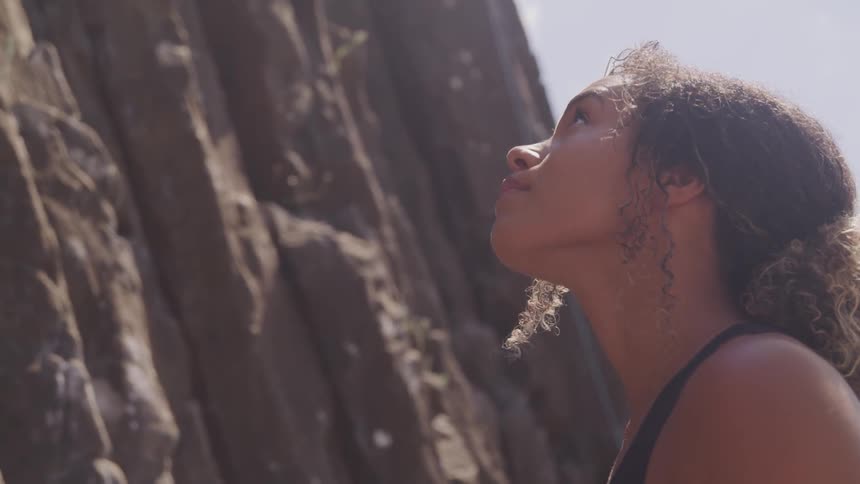 A black curly woman looking at the cliff