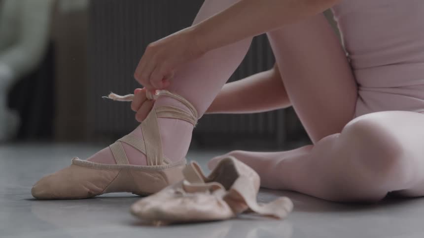 A girl is putting ballet shoes on