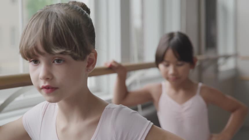 Ballerinas exercise at bar in dance studio