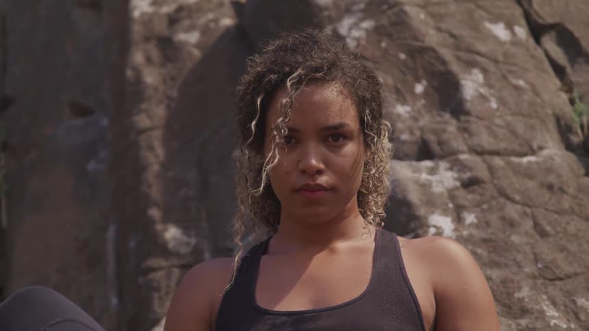 Black woman sits on a rock in the rocky place