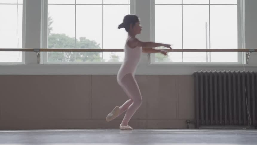 A little girl practices ballet in a room