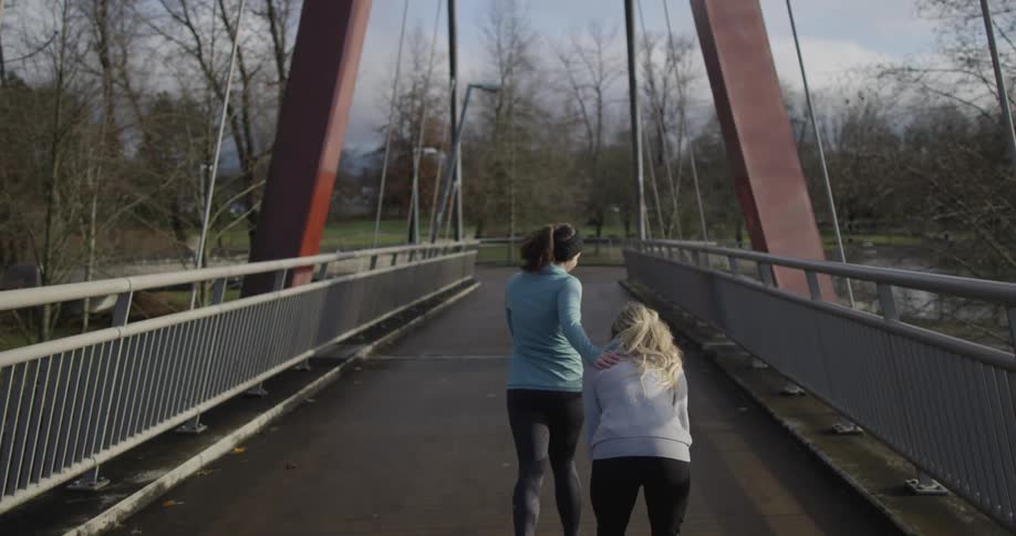 Women jogging across a bridge