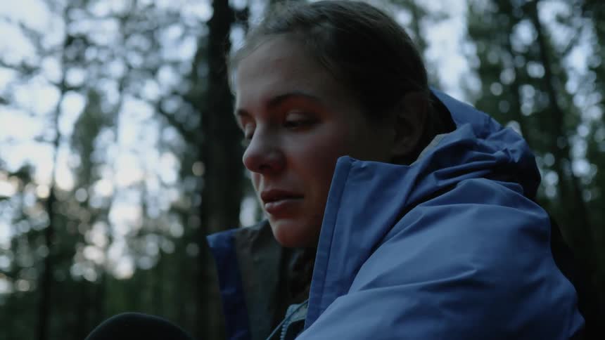 A woman with blue jacket sit in the forest