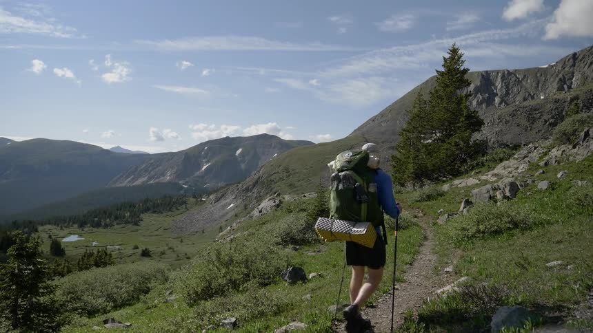 A man and woman hike along a mountain side trail