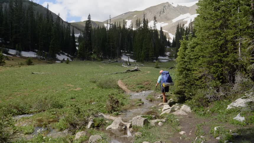 A woman uses walking sticks as she hikes down a trail