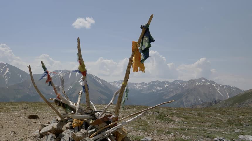 Torn flags hang on sticks piled up on top of a mountain