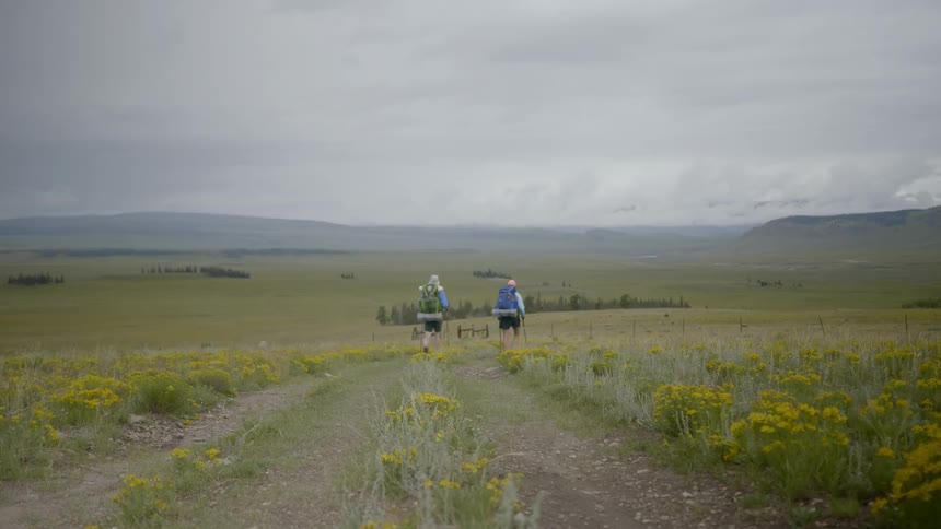 Man and woman hike on the road on a cloudy day