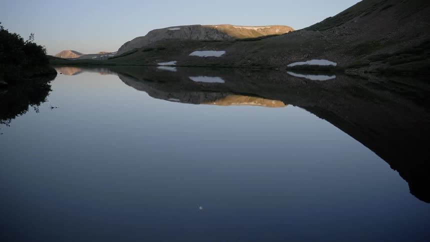 A still body of water showing a reflection of its far shore
