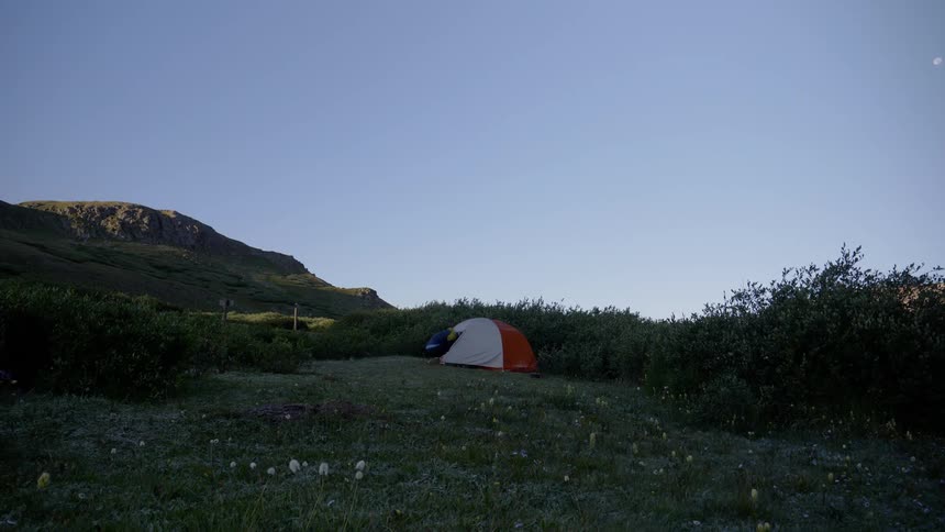 Static shot of a person entering a tent at dusk