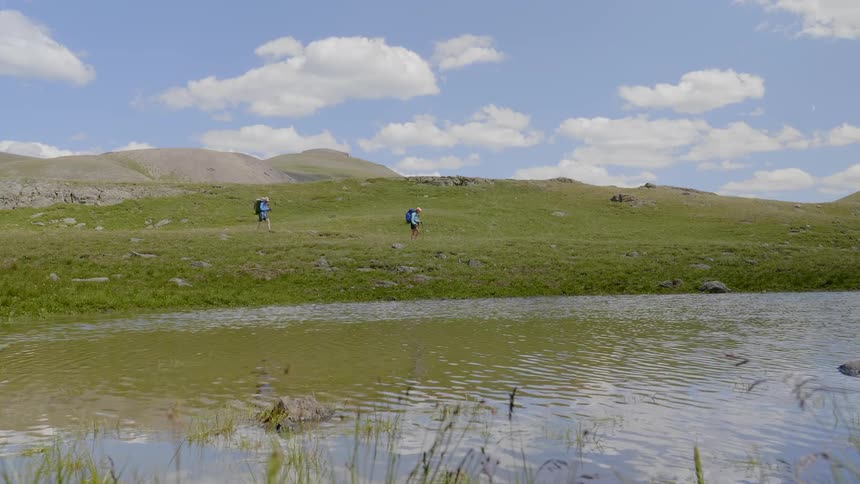 Man and woman walk on the plain next to the lake