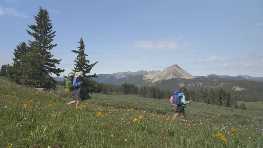 People hike down a grassy hill