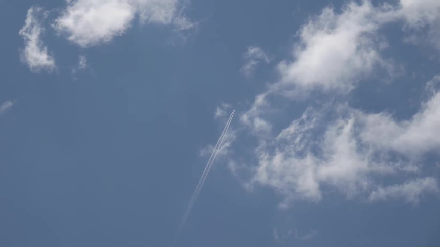 An airplane leaves two streaks of white as it flies in a blue sky