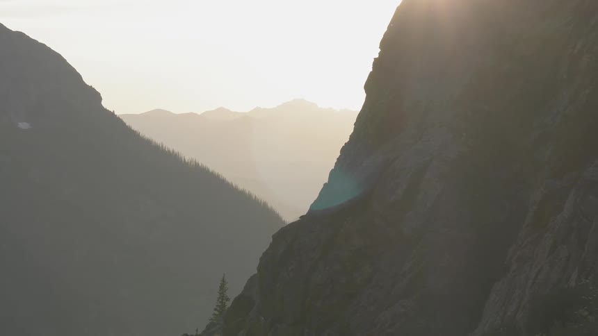 The sun shining onto a mountain side in a large mountain range