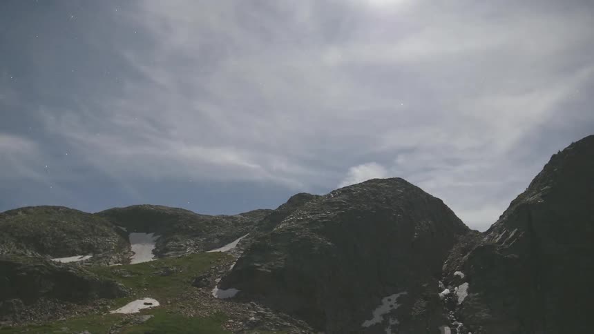 Several hilltops covered in green vegetation sit beneath the passing clouds in the sky above
