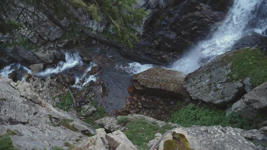 A waterfall runs through a gorge thats descending through rock walls