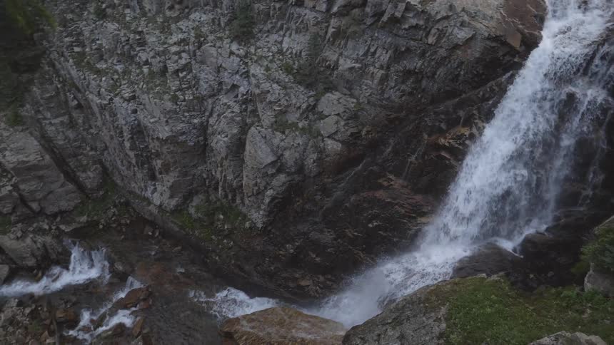 A scenery of a great waterfall sitting on a big rock