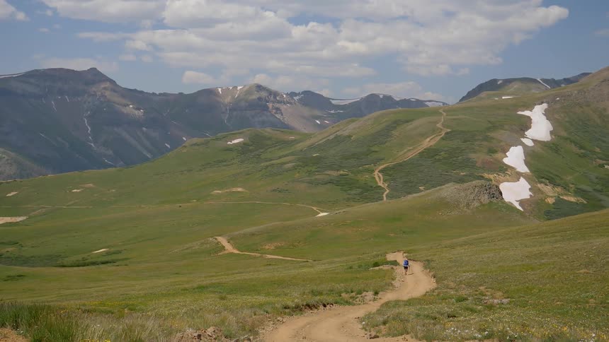 A person walks a long path through an open grassland
