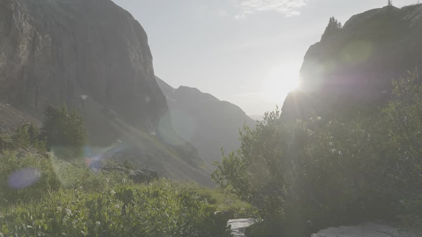 The sun rising between a mountain canyon