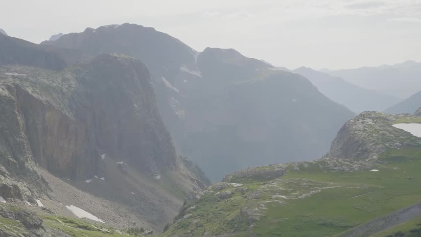 Grass and rocks sit near the mountains in the fog